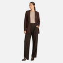 Modelo con chaqueta de punto larga marrón de Freequent combinada con pantalón de vestir.