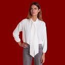 Mujer con camisa blanca de lazo combinada con vaqueros grises
