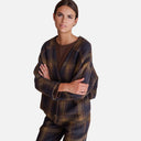 Modelo con chaqueta de cuadros azul marino y marrón de Studio Manna combinada con pantalón a juego.