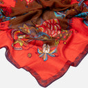 Detalle del tejido de seda y del estampado floral del pañuelo Surkana con flores en tonos rojos y marrones