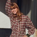 Modelo con blusa Feeka de cuadros burdeos y beige con volante delantero y mangas abullonadas.