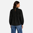 Vista trasera de la blusa negra Feeka con cuello fruncido, espalda con abertura y mangas largas de volumen.
