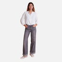 Look completo con camisa blanca de Studio Manna combinada con vaquero gris.
