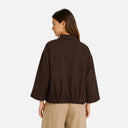 Modelo mostrando la espalda de la chaqueta chocolate de Freequent con corte relajado y bajo elástico