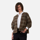 Vista frontal de chaqueta de cuadros Orfeo para mujer en tonos marrones y tierra con camisa blanca y pantalón negro.
