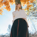 Look con jersey de punto fino crudo de PAN Producto Básico y falda negra de rayas en un parque