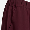 Pantalón fluido granate de mujer de pernera ancha detalle.