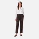 Modelo con pantalón recto de vestir Freequent en color marrón oscuro combinado con blusa blanca